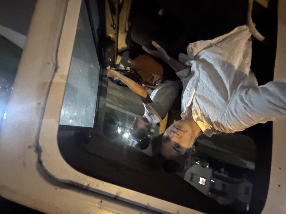 Two people in the truck's cab at night, one driving, one taking the photo